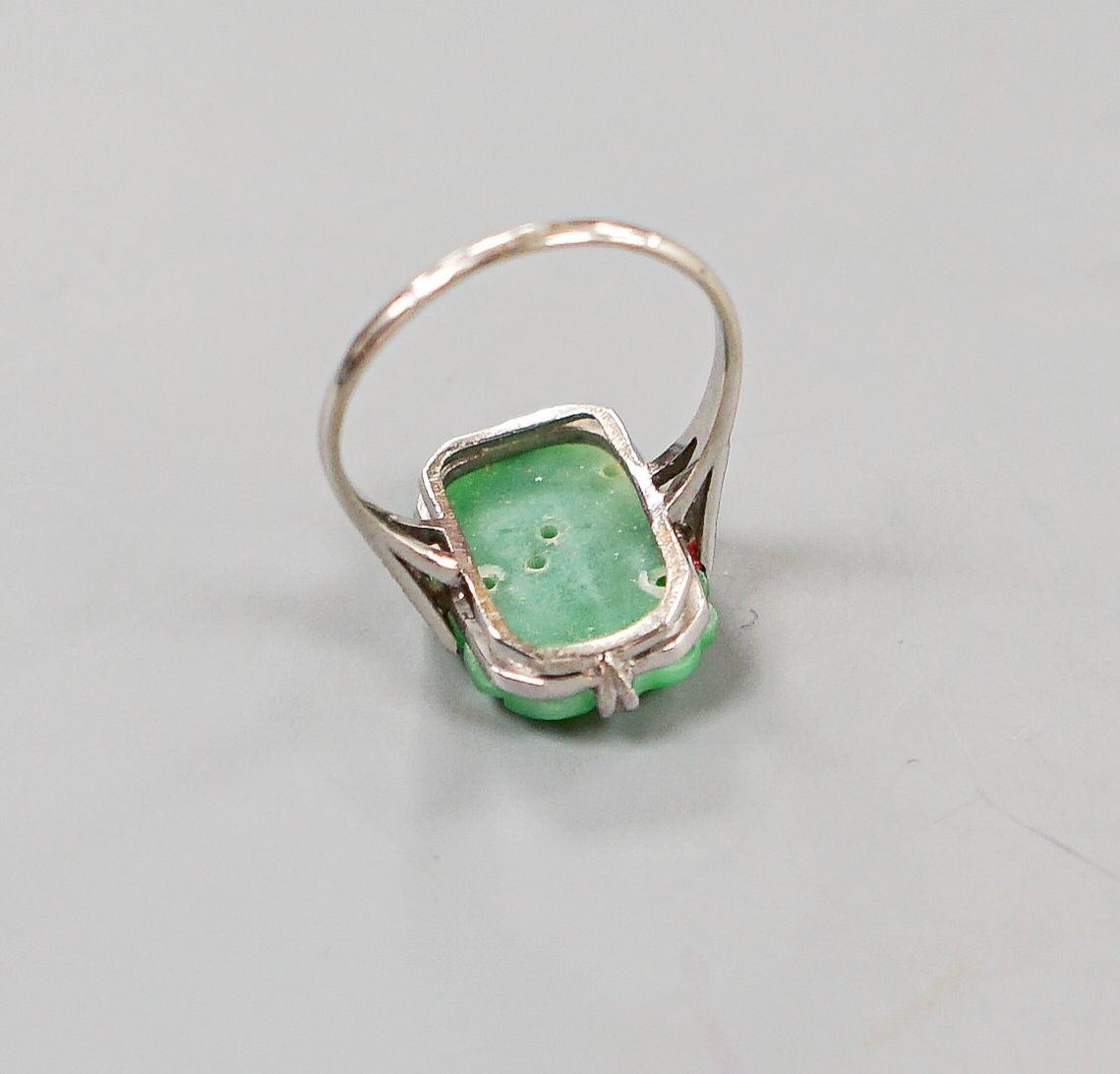 A 1920's 18ct, plat and carved jadeite oval dress ring, size O, gross weight 3.8 grams.